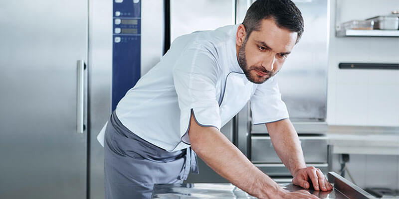 Chef cleaning restaurants kitchen equipment